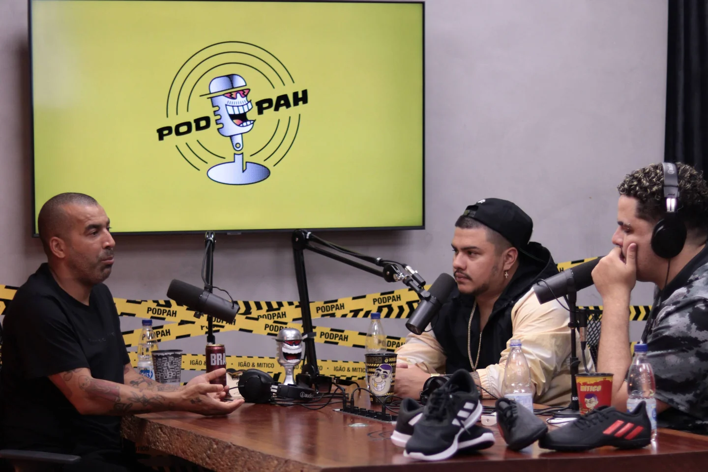 Conversa entre convidado e apresentadores no Podpah, com microfones e fones durante a gravação